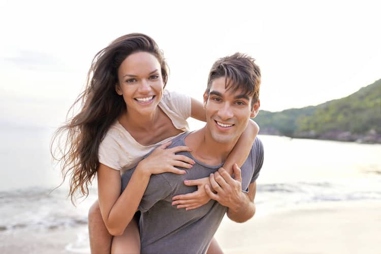 A cropped shot of a young man giving his girlfriend a piggyback ride on the beach
