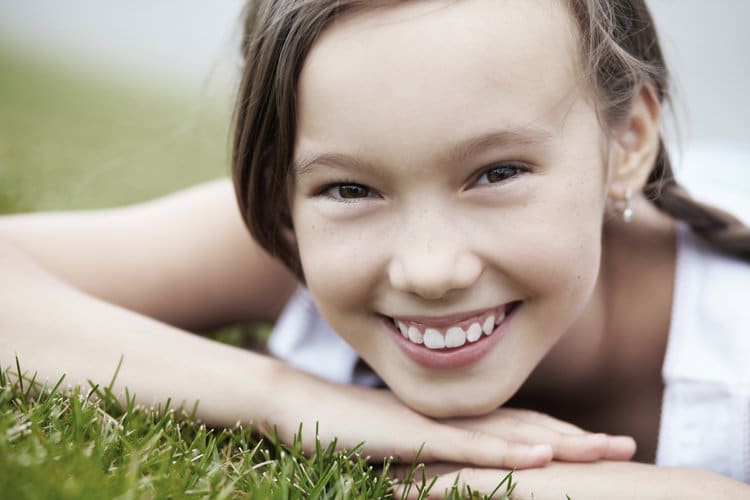 A young girl laying in the grass and smiling