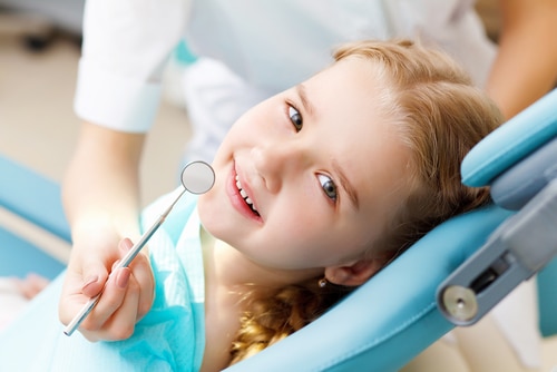 A young girl smiling while having her teeth examined
