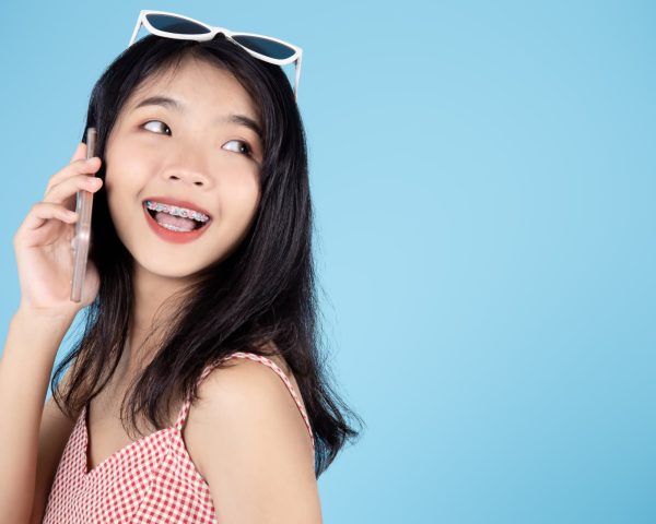 Happy Asian woman calling phone on blue background and copy space.